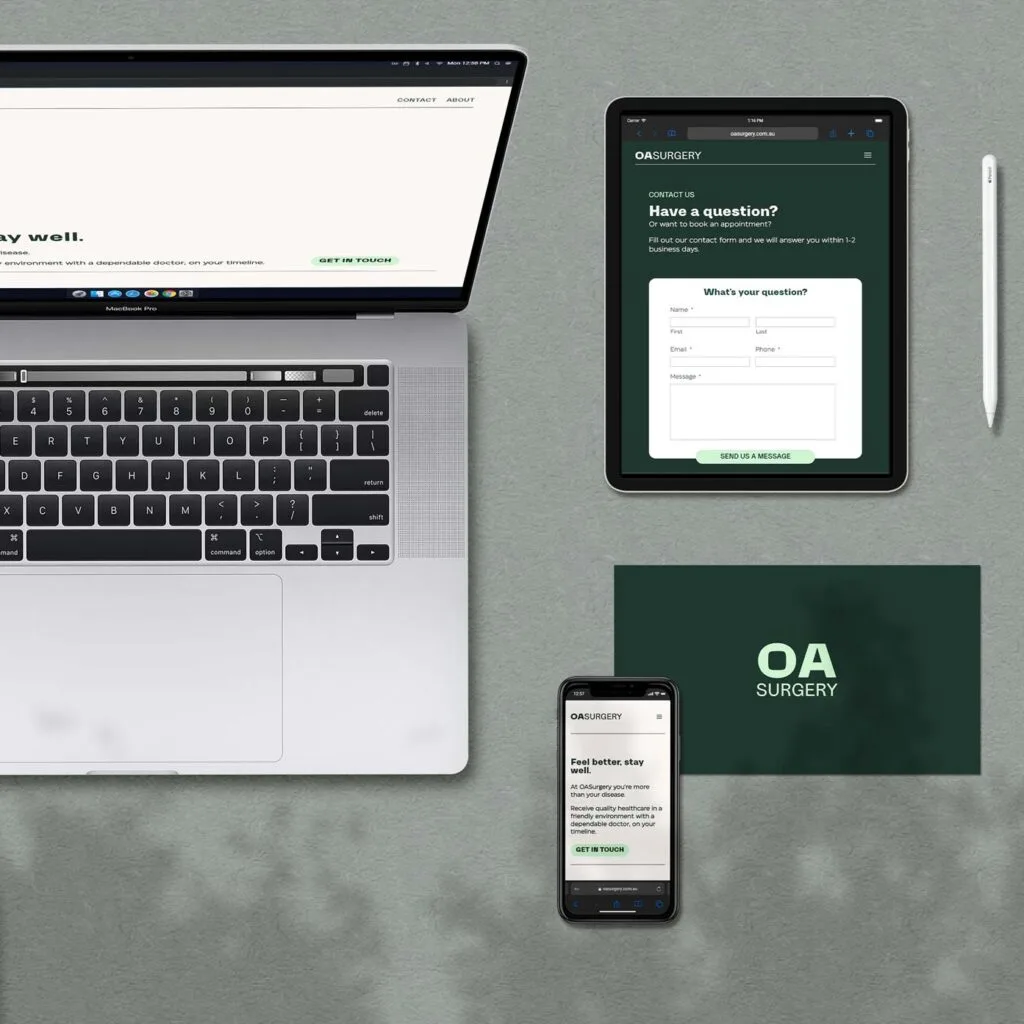 laptop, tablet, smartphone, and pen arranged on a surface displaying oa surgery website. laptop shows homepage, tablet shows form, smartphone shows mobile view, and envelope reads "oa surgery.