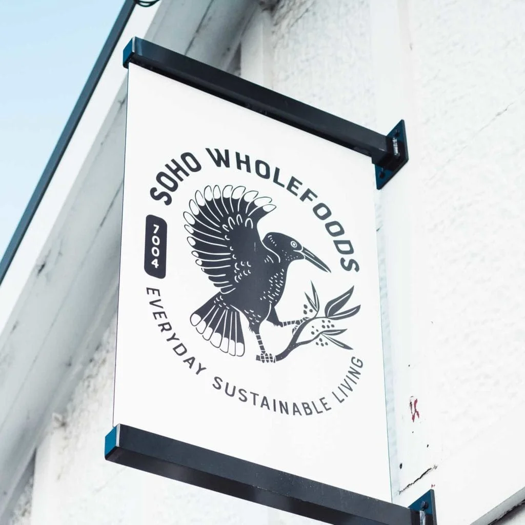 A sign that says "soho wholefoods" on the side of a building, showcasing the brand identity for the store.