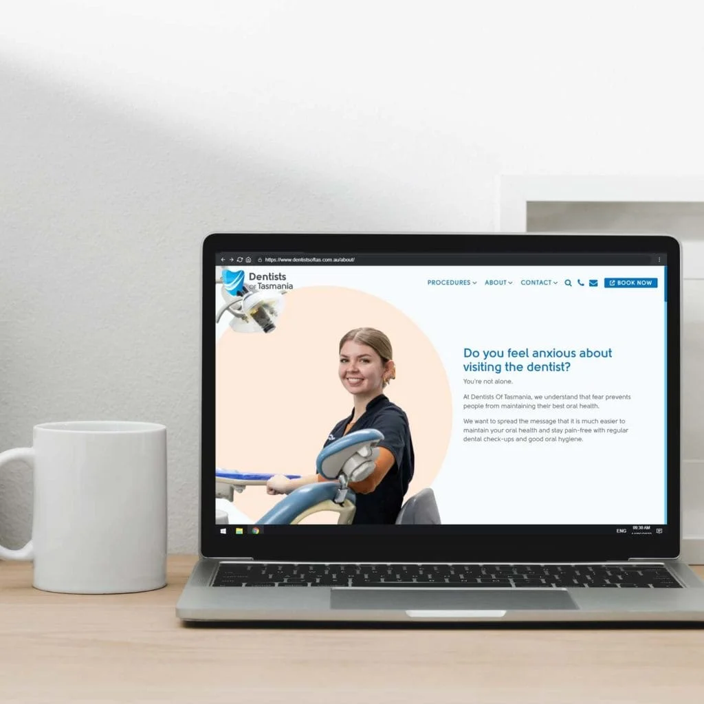 A laptop computer with a woman sitting in front of it, engaged in web design for a dentist.