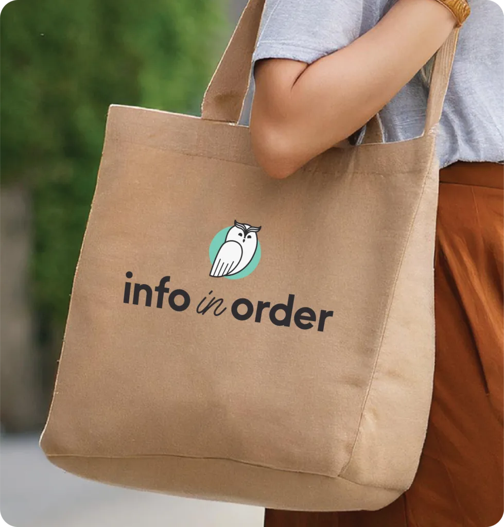 woman holding a beige tote bag with an owl logo and the text "info in order.